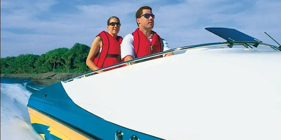 Man driving a boat with a female passenger by his side